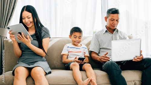 Fotografía An Asian family engrossed in gadgets at home neglecting togetherness