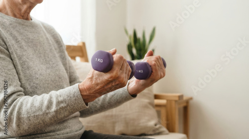 Osteoporosis arm exercise supports bone strength as older adult lifts light weight at home with focused determination