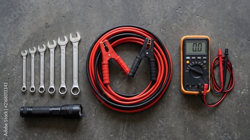 Automotive repair tools flat lay with jumper cables and multimeters