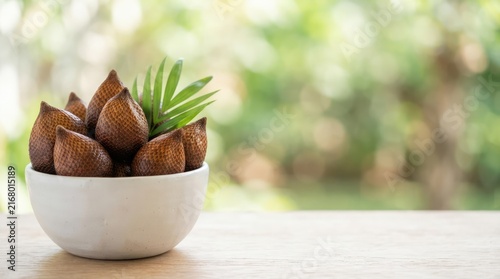 Fresh snake fruit served in a white ceramic bowl on a rustic wooden table against a soft blurred natural garden background for healthy diet