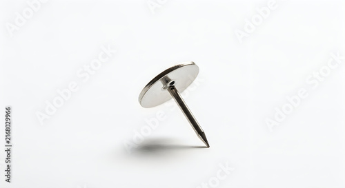 Silver push pin standing upright on plain surface