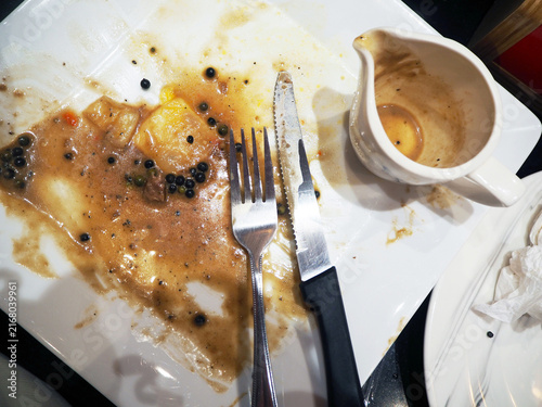 Quadro su tela A dirty plate with leftover food, cutlery, and sauce, indicating the end of a me