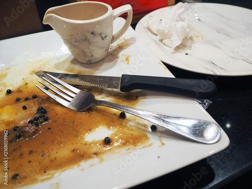Konstfotografi Messy plate after a delicious meal with fork, knife, and gravy boat on the side