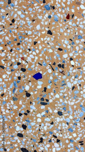 Top-down macro frame of terrazzo texture. Multi-colored white quartz, black basalt & cobalt blue glass chips embedded in a light orange concrete base. Vintage mid-century modern abstract flooring.