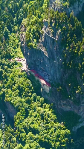 Vertical video. Altindere, Trabzon Province, Turkey. Sumela Monastery, a Greek Orthodox complex carved into a sheer cliff face, aerial drone view over dense coniferous forest and the winding Altinder