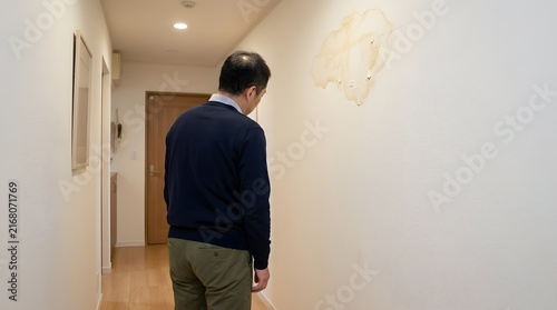 Fototapeta 壁の雨漏りや水漏れのシミを見つめる男性の後ろ姿