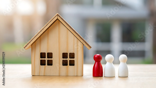Miniature wooden house model with two white figurines representing family or couple on wooden table