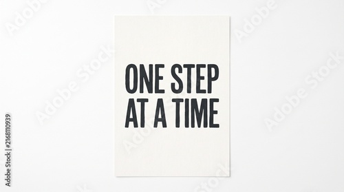 Motivational Quote One Step At A Time Written on White Paper.