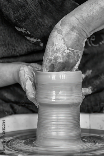 potter models the clay on a potter's wheel