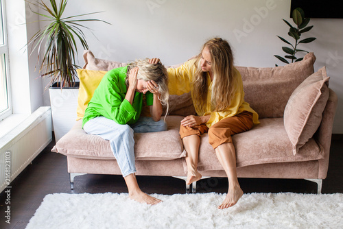 Canvastavla Woman crying on sofa while friend comforting her