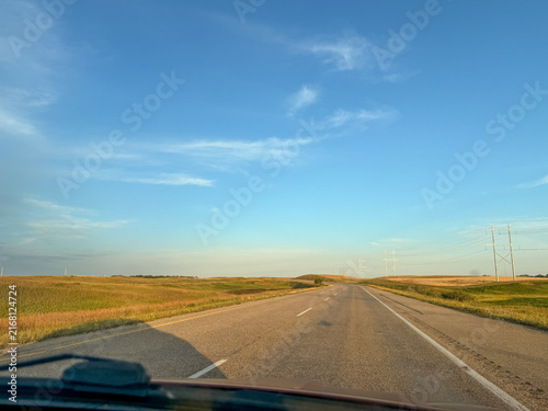 Driver point of view on rural two-lane highway through golden prairie landscape