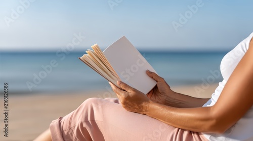 Woman reading a book on the beach during a sunny day