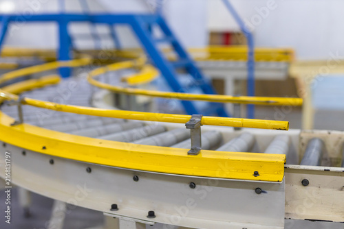 Картината върху платно Empty yellow curve roller conveyor belt inside modern industrial manufacturing f