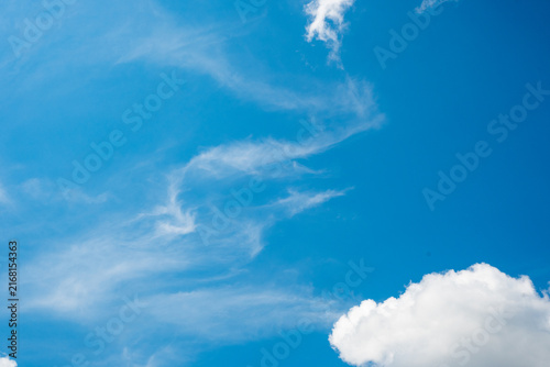 Фотография Bright blue sky with wispy white cirrus clouds and a fluffy cloud in the corner