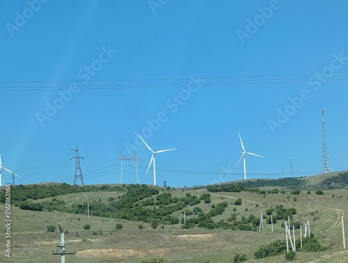 Canvastavla A group of modern wind turbines standing across the green landscape of Georgia on a bright summer day, surrounded by open fields, hills, and natural scenery