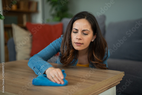 Фотография Woman diligently cleaning table surface with microfiber cloth