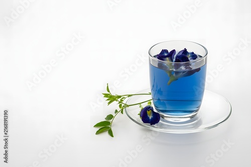 A glass of vibrant blue butterfly pea flower tea with fresh petals and leaves, presented on a white background, highlighting a natural and healthy botanical wellness drink.