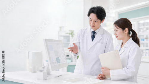 薬局でモニターの処方連携画面を確認する薬剤師2人
