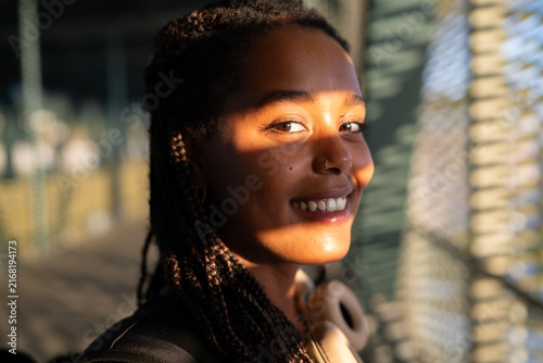 Young African American woman smiles warmly in natural sunlight