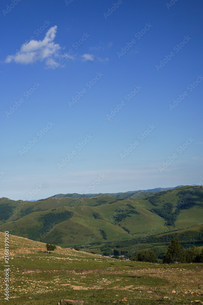 Fototapeta premium Wide View of Green Rolling Mountains Under Clear Blue Sky