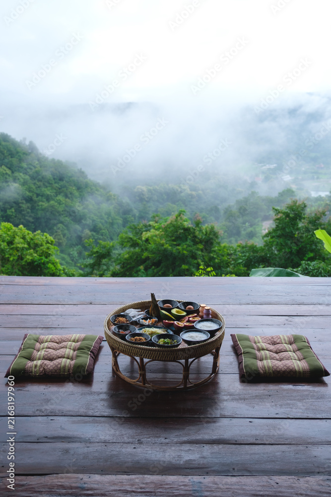 Fototapeta premium A set of breakfast on Northern Thai traditional dining table with foggy mountain views
