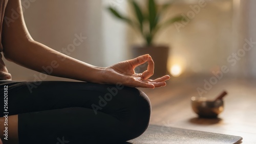 Close up of hand in yoga mudra, woman meditating on mat in cozy home