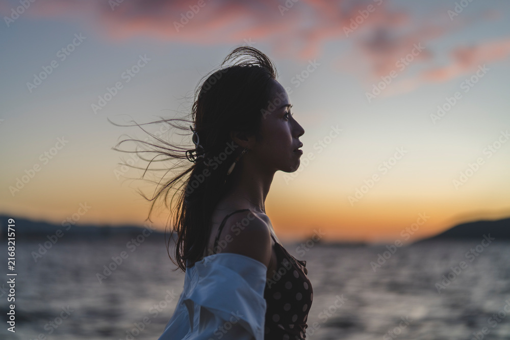 Fototapeta premium 夕暮れの海にいる女性
