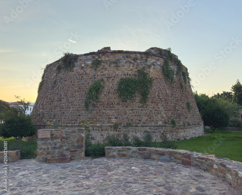 Quadro su tela Massive weathered stone bastion draped in greenery at sunset in Chios Town, Gree