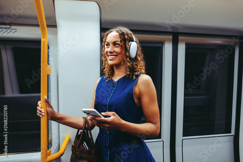 Woman listens to music on subway train using smartphone