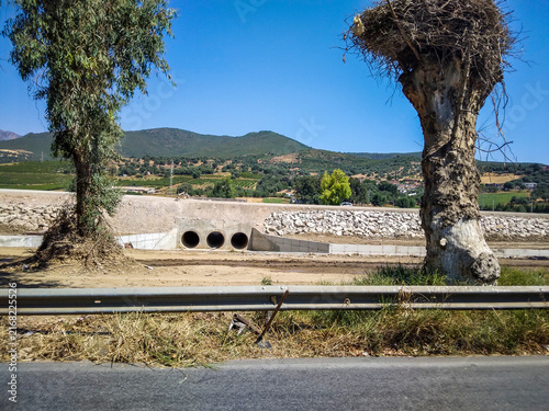 Foto Concrete drainage pipes embedded in a dry earthen embankment landscape featuring