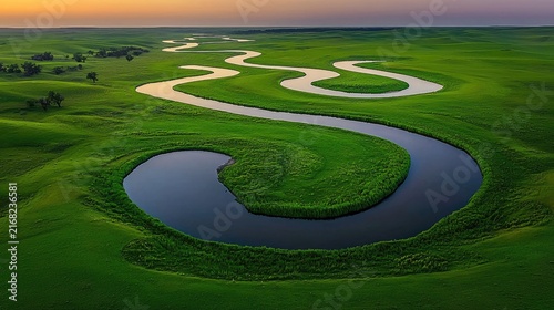 Serpentine river meandering through verdant, rolling landscape.