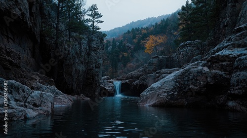 Serene mountain stream cascading into a tranquil pool surrounded by dark rock formations.