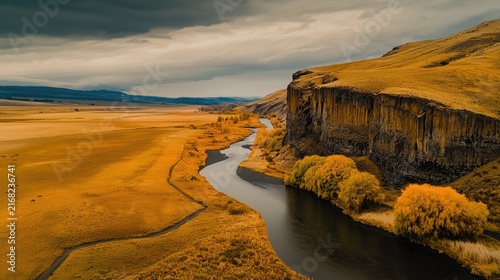 Aerial view of a winding river cutting through a golden landscape.