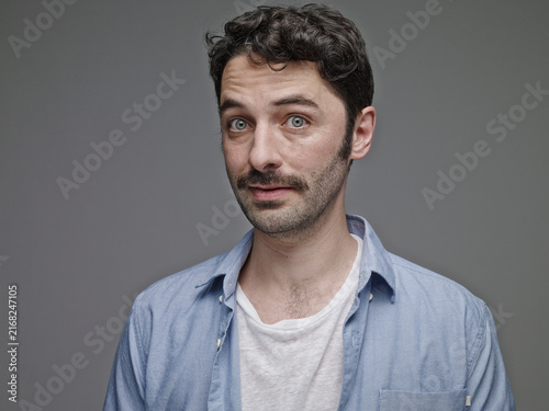 Portrait of sceptical man in front of grey background