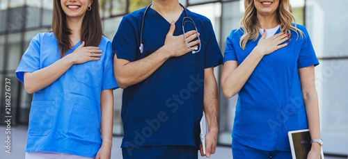 Cuadro en lienzo Medical Team in Scrubs Standing United With Hands Over Hearts Showing Commitment
