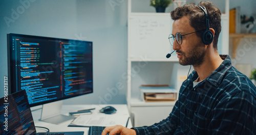 Young Caucasian male technical support specialist wearing headset speaks on computer at office. Professional call center help desk, Cyber security operator service, Online client consultation concept.