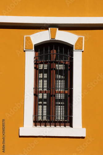 An arched window on a yellow wall. An architectural detail from a century-old house.