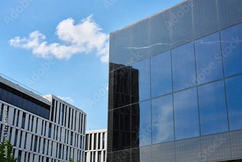 Cuadro en lienzo Modern reflective glass building under blue sky with clouds
