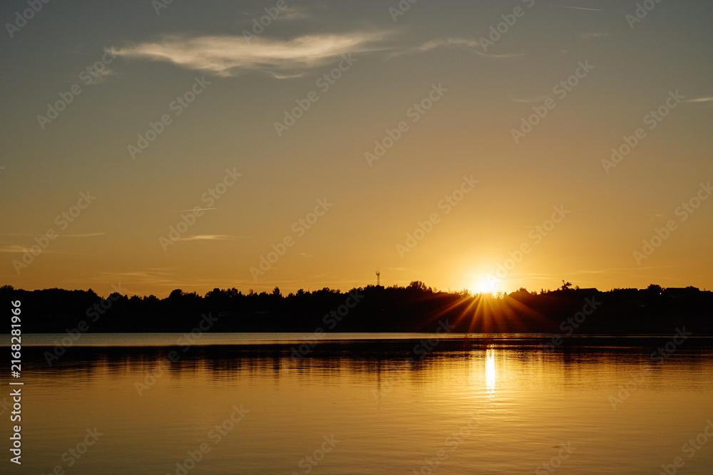 Naklejka premium Golden sunset over calm lake with sun reflection