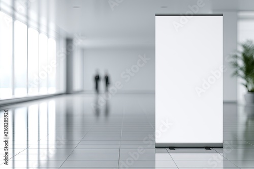 A blank display banner stands in a modern, sunlit atrium with blurred figures