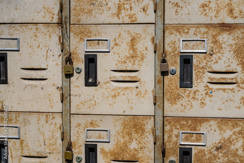 Canvastavla Rusty Lockers Detail: A close-up shot reveals the texture and aging of weathered metal lockers, showcasing rust, grime, and sturdy padlocks, hinting at stories within