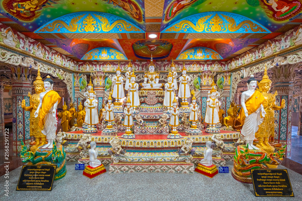 Fototapeta premium White Buddha statues with Thai prayer sign and do not touch warning sign at Wat Sri Uthumphon, Mueang Nakhon Sawan District, Nakhon Sawan, Thailand, set in a colorful decorated hall.