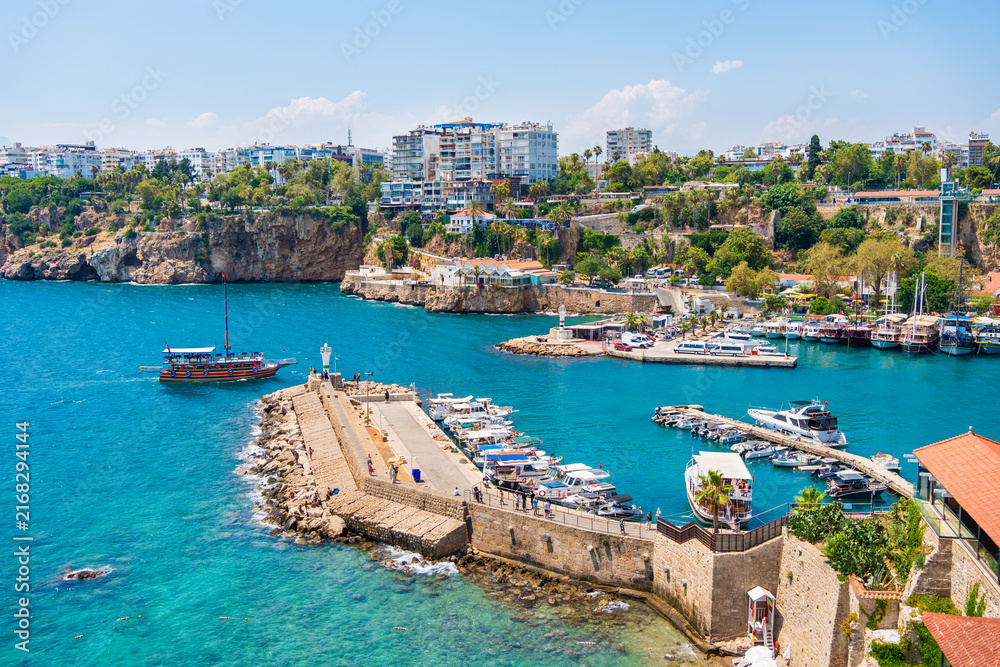 Fototapeta premium Tourist ships and fishing boats in the port of Old Town in Antalya, Turkey. Blue sea and the blue sky at sunny day.