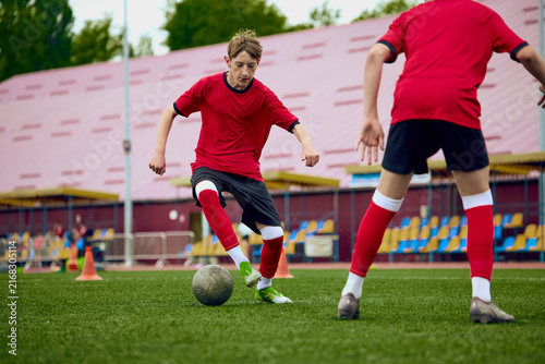 Obraz na plátně Teenage male football attacker facing defender during competitive practice game