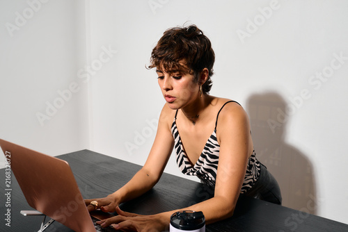 Businesswoman working at Office. DIrect flash shot. She types intently on her laptop, focused on a task
