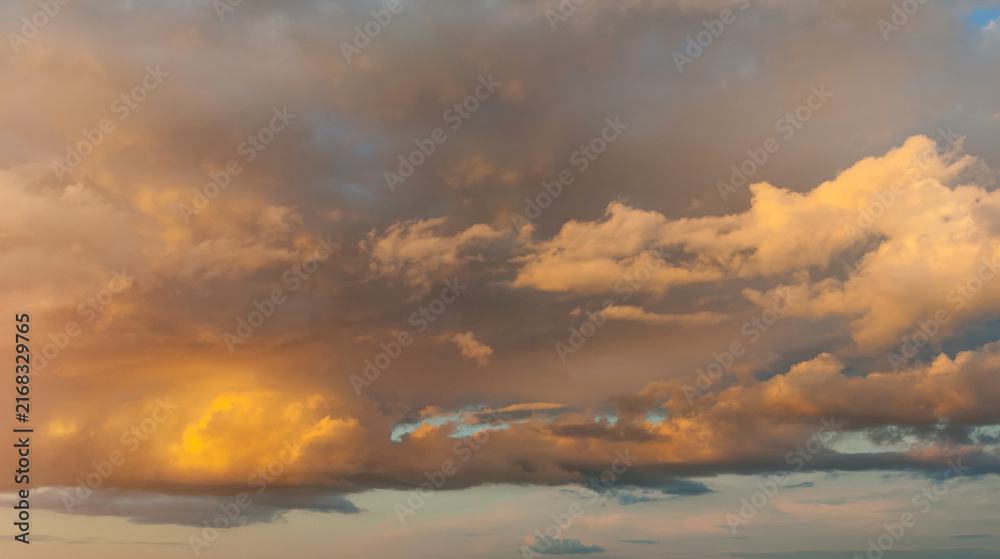 Fototapeta premium Panoramic wide angle sunset sky background, cloudscape with golden, yellow and orange clouds in the evening sunny sky