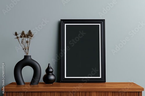Black framed art on wooden dresser with decorative vases and dried botanicals