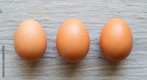 Three hard-boiled eggs on wooden surface