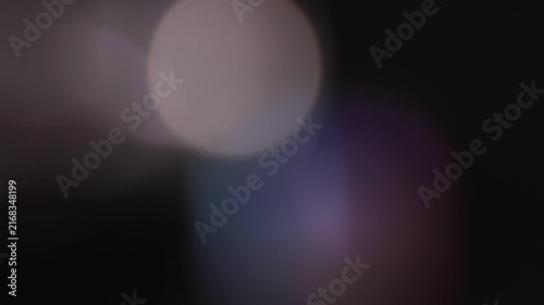 Rotating circular bokeh changing blue, green and white hues on a black background for ambient screens, overlays and abstract design