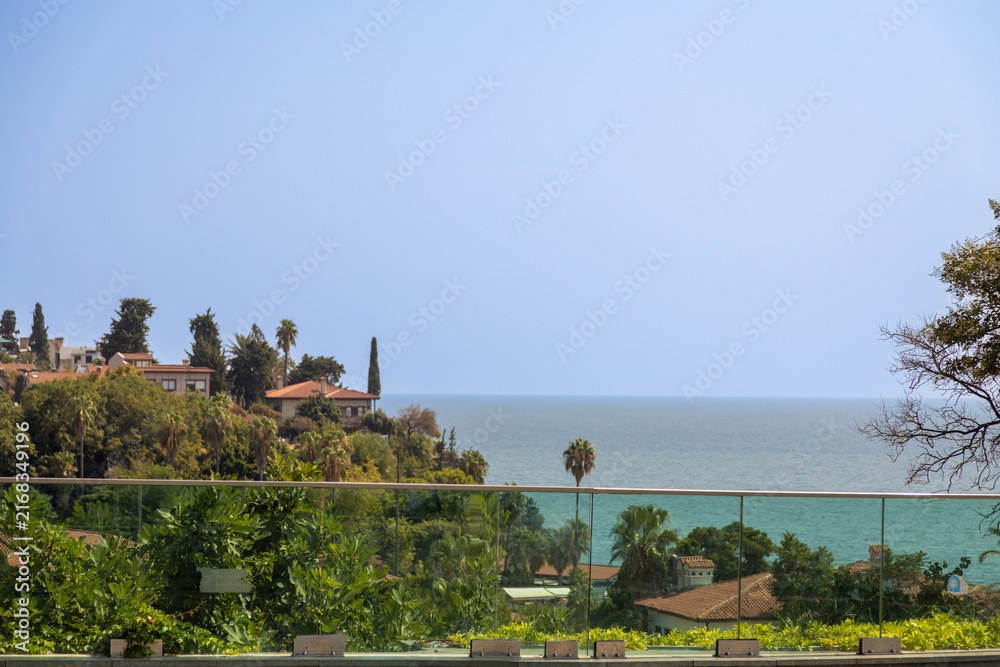 Fototapeta premium Scenic view of Kaleici old town from a modern glass railing observation deck in Antalya, Turkey. Mediterranean coastal resort cityscape, blue sea, and travel atmosphere.